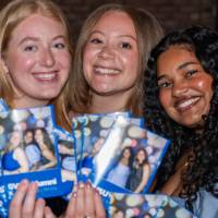 Three grads smile with their photo booth photo prints